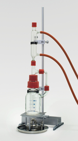 Das Bild zeigt ein chemisches Experimentiergerät mit einer Glasflasche, die ein Volumen von 200 ml anzeigt, sowie mehreren Verbindungsrohren und einem Heizgerät darunter. Das gesamte Setup ist auf einem stabilen Stativ montiert, ideal für Bildungszwecke im Labor.