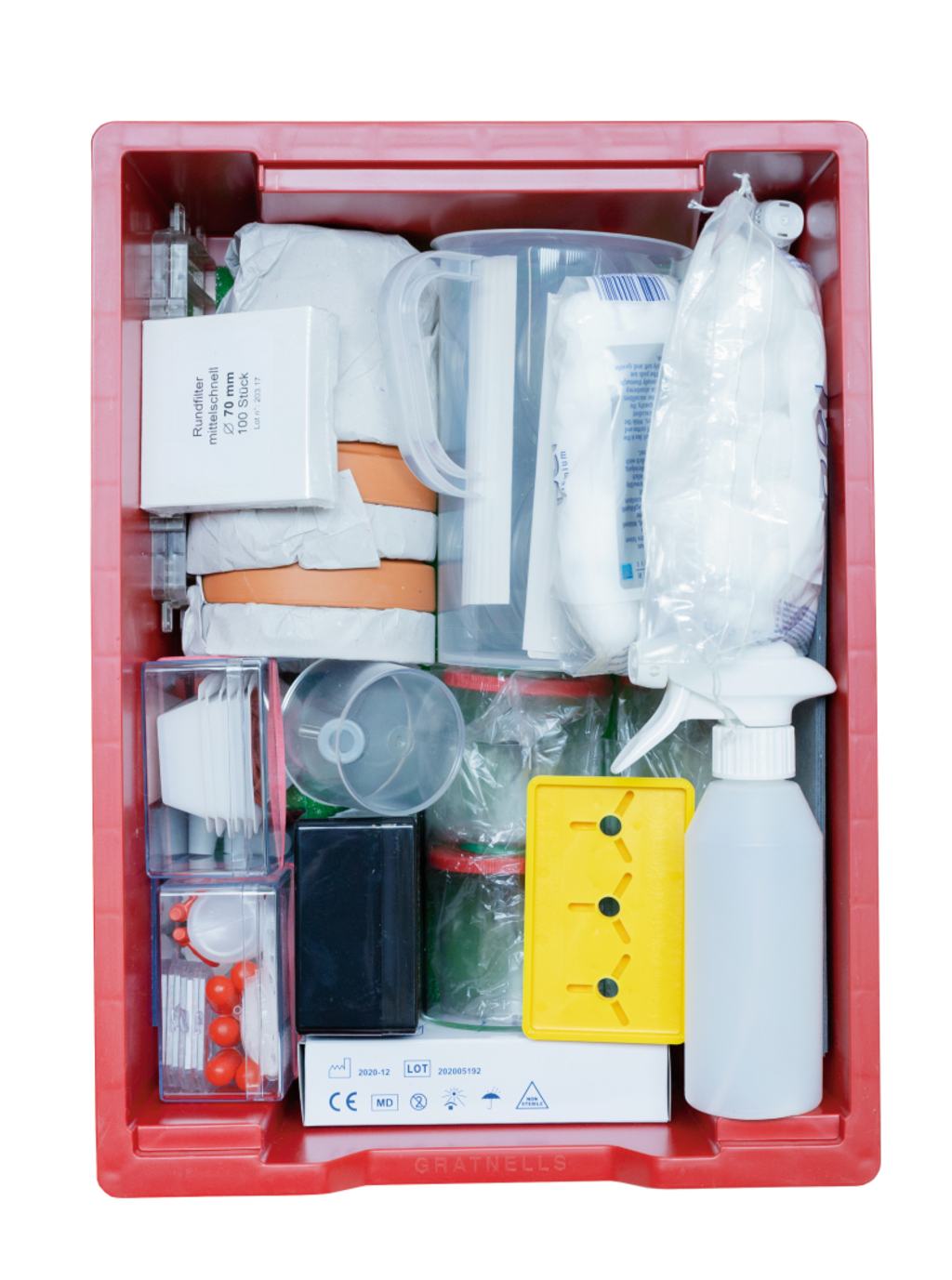 Das Bild zeigt eine rote Aufbewahrungsbox, die mit verschiedenen Experimentiermaterialien gefüllt ist, darunter Messbecher, farbige Behälter und ein Sprühflasche. Diese Materialien sind für den Einsatz in Bildungseinrichtungen konzipiert, um Experimente durchzuführen.