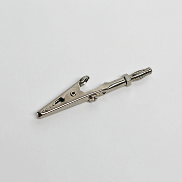 Das Bild zeigt eine silberne Krokodilklemme, die typischerweise in Experimenten und elektrischen Schaltkreisen verwendet wird. Sie hat eine praktische Befestigungsvorrichtung zur sicheren Verbindung von Drähten oder Bauteilen.