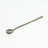 Das Bild zeigt einen langen, schlanken Löffel aus Metall auf einem hellen Hintergrund. Er eignet sich wahrscheinlich für Experimentierzwecke im Bildungsbereich, wie das Messen oder Mischen von Flüssigkeiten.