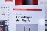 Das Bild zeigt ein Demo-Set mit dem Titel "Grundlagen der Physik" von Cornelsen Experimenta. Es ist Teil eines Online-Angebots für Experimentierbedarf im Bildungsbereich und zeigt verschiedene Experimente und Materialien zur Veranschaulichung physikalischer Konzepte.