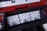 Das Bild zeigt eine gepolsterte Box mit mehreren analogen Messgeräten, die zur Messung von Strom (A), Spannung (V) und Millivolt (mV) verwendet werden. Die Geräte sind übersichtlich angeordnet und verfügen über klare Skalen für präzise Ablesungen.