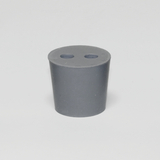 Das Bild zeigt einen grauen Zylinder mit einer offenen Oberseite, die zwei gleich große Löcher aufweist. Dieses Experimentiergerät wird wahrscheinlich in Schulen oder Bildungseinrichtungen für wissenschaftliche Versuche verwendet.