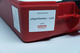 Das Bild zeigt ein rotes Experimentier-Set mit dem Titel "eXperTeenies – Luft" von Cornelsen Experimenta. Es handelt sich um ein Set für wissenschaftliche Experimente, das speziell für das Bildungswesen im Bereich Luft und ihre Eigenschaften konzipiert ist.