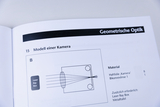 Das Bild zeigt eine Seite aus einem Experimentierhandbuch, das ein Modell einer Kamera beschreibt. Es enthält eine schematische Darstellung zusammen mit den benötigten Materialien für das Experiment, darunter eine Haftrfolie und eine Bikonvexlinse.
