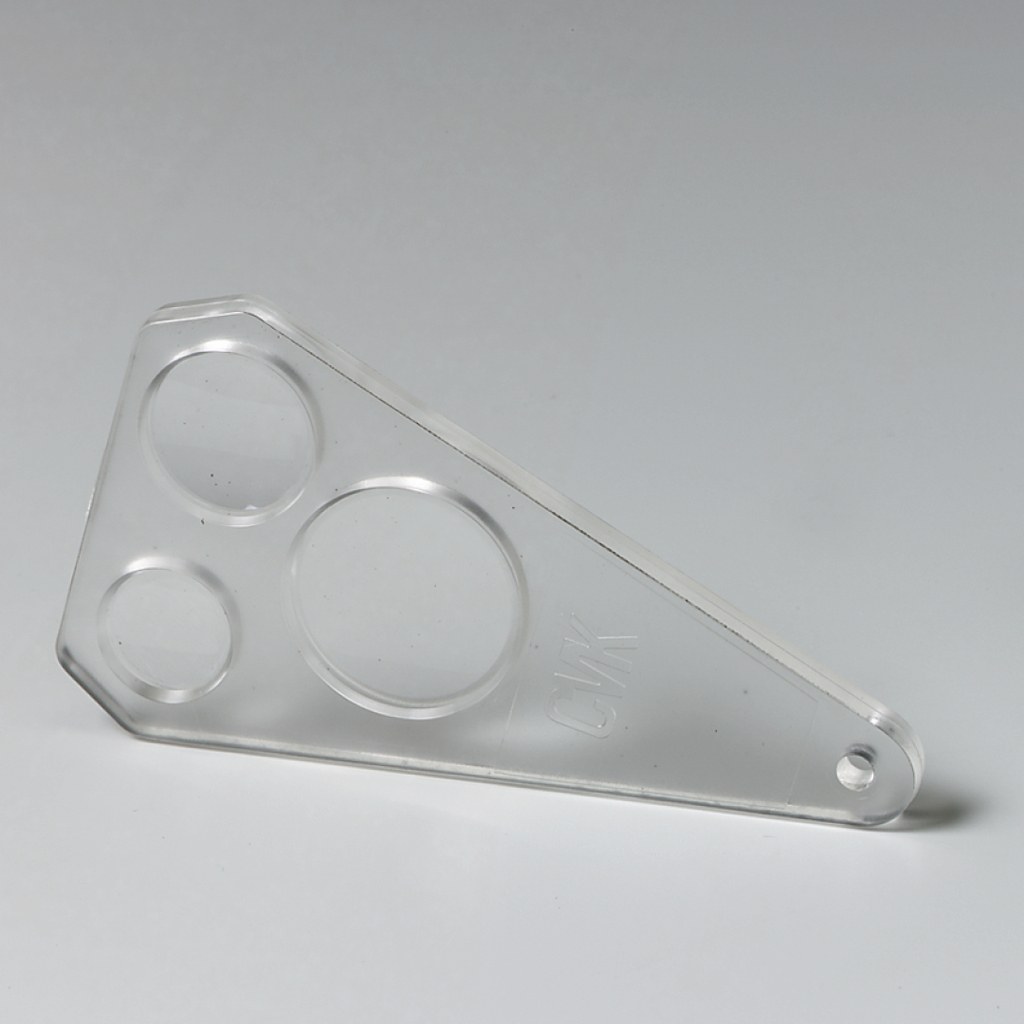 Das Bild zeigt ein transparenter Kunststoffschieber mit drei unterschiedlich großen runden Ausschnitten. Dieses Werkzeug wird häufig im Bildungsbereich für Experimentierzwecke verwendet, um Flüssigkeiten oder andere Materialien zu testen.