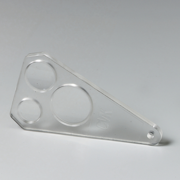 Das Bild zeigt ein transparenter Kunststoffschieber mit drei unterschiedlich großen runden Ausschnitten. Dieses Werkzeug wird häufig im Bildungsbereich für Experimentierzwecke verwendet, um Flüssigkeiten oder andere Materialien zu testen.