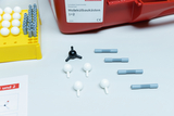 Das Bild zeigt einen Molekülbaukasten mit verschiedenen bunten Komponenten zur Erstellung von Modellen. Sichtbar sind eine gelbe Basis mit weißen und grauen Kugeln sowie eine Anleitung in Form eines Blattes.