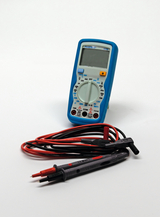 Das Bild zeigt ein digitales Multimeter in Blau, das zur Messung von elektrischen Größen dient. Unter dem Multimeter befinden sich Messleitungen in Rot und Schwarz, die verwendet werden, um elektrische Verbindungen herzustellen.