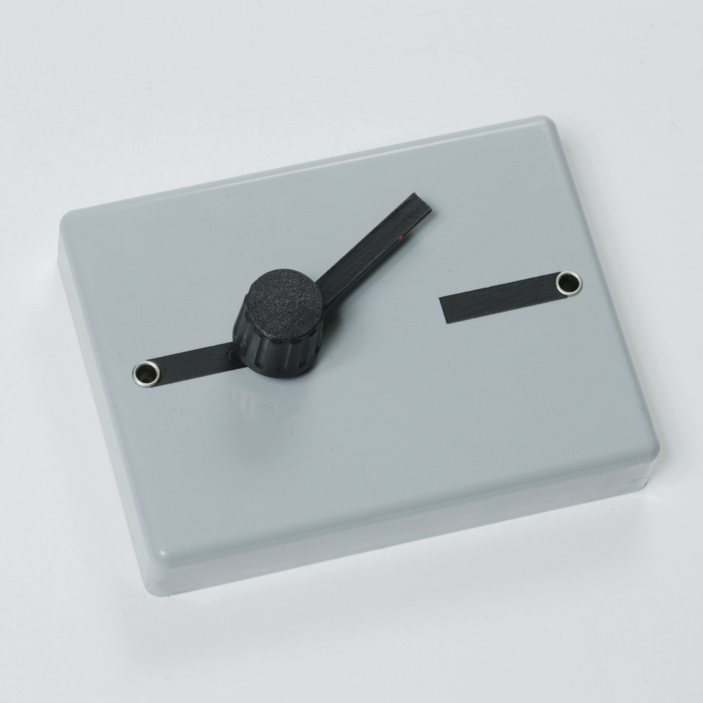 Das Bild zeigt ein graues Kunststoffgehäuse mit einem schwarzen Drehregler und zwei Anschlussbuchsen. Es scheint sich um ein elektrisches oder experimentelles Gerät zu handeln, das für Bildungszwecke im naturwissenschaftlichen Unterricht genutzt wird.