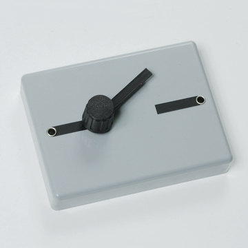 Das Bild zeigt ein graues Kunststoffgehäuse mit einem schwarzen Drehregler und zwei Anschlussbuchsen. Es scheint sich um ein elektrisches oder experimentelles Gerät zu handeln, das für Bildungszwecke im naturwissenschaftlichen Unterricht genutzt wird.