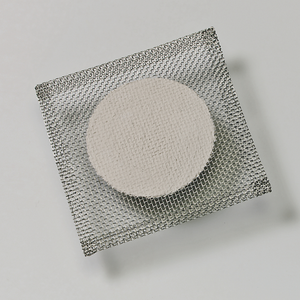 Das Bild zeigt eine runde, helle Probe, die auf einem feinmaschigen Drahtgitter platziert ist. Dieses Setup könnte für Experimente im Bildungsbereich verwendet werden, möglicherweise im Bereich der Chemie oder Materialwissenschaften.