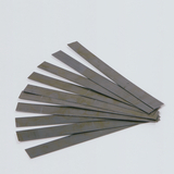 Das Bild zeigt eine Gruppe von dünnen, rechteckigen Metallstreifen, die übereinanderliegend angeordnet sind. Diese Streifen könnten als Experimentiermaterial im Bildungsbereich verwendet werden, möglicherweise für physikalische oder technische Anwendungen.