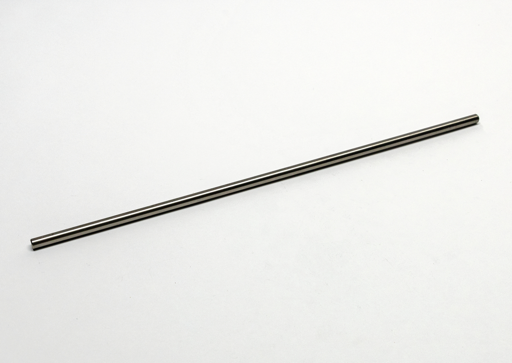 Das Bild zeigt einen langen, schlanken Metallstab, der auf einer neutralen, hellen Fläche liegt. Er könnte für verschiedene Experimente oder Messungen im Bildungsbereich verwendet werden.