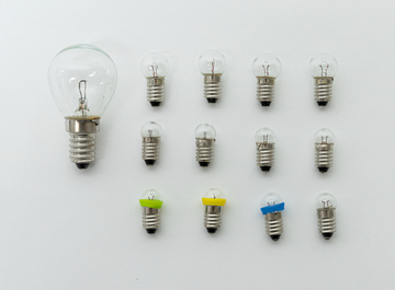 Das Bild zeigt eine Anordnung von Glühbirnen in verschiedenen Größen, darunter eine größere Birne links und mehrere kleinere Birnen in zwei Reihen. Einige der kleineren Birnen haben farbige Ringe, die wahrscheinlich zur Kennzeichnung dienen.
