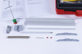 Das Bild zeigt verschiedene Komponenten für Experimente, darunter Metall- und Kunststoffteile sowie eine Feder und ein Faltblatt mit Anleitungen. Diese Materialien sind für Lehrzwecke im deutschen Bildungswesen konzipiert, um praktische Experimente durchzuführen.