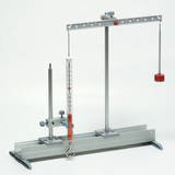 Das Bild zeigt ein physikalisches Versuchsaufbau mit einem Hängependel und einer Messskala. Der Apparat wird verwendet, um Experimente zur Untersuchung von Kräften und Bewegungen durchzuführen.