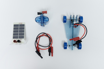 Das Bild zeigt verschiedene Komponenten für ein Experimentierprojekt: ein Solarpanel, einen kleinen Motor und ein Modellauto. Diese Teile ermöglichen es Lernenden, grundlegende Prinzipien der Energieumwandlung und Elektromechanik zu erforschen.