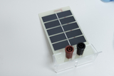 Das Bild zeigt ein Solarzellenmodul mit mehreren kleinen Solarzellen in einer Reihe. Am unteren Rand befinden sich zwei Anschlüsse in rot und schwarz, die zur Verbindung mit einer Schaltung dienen.