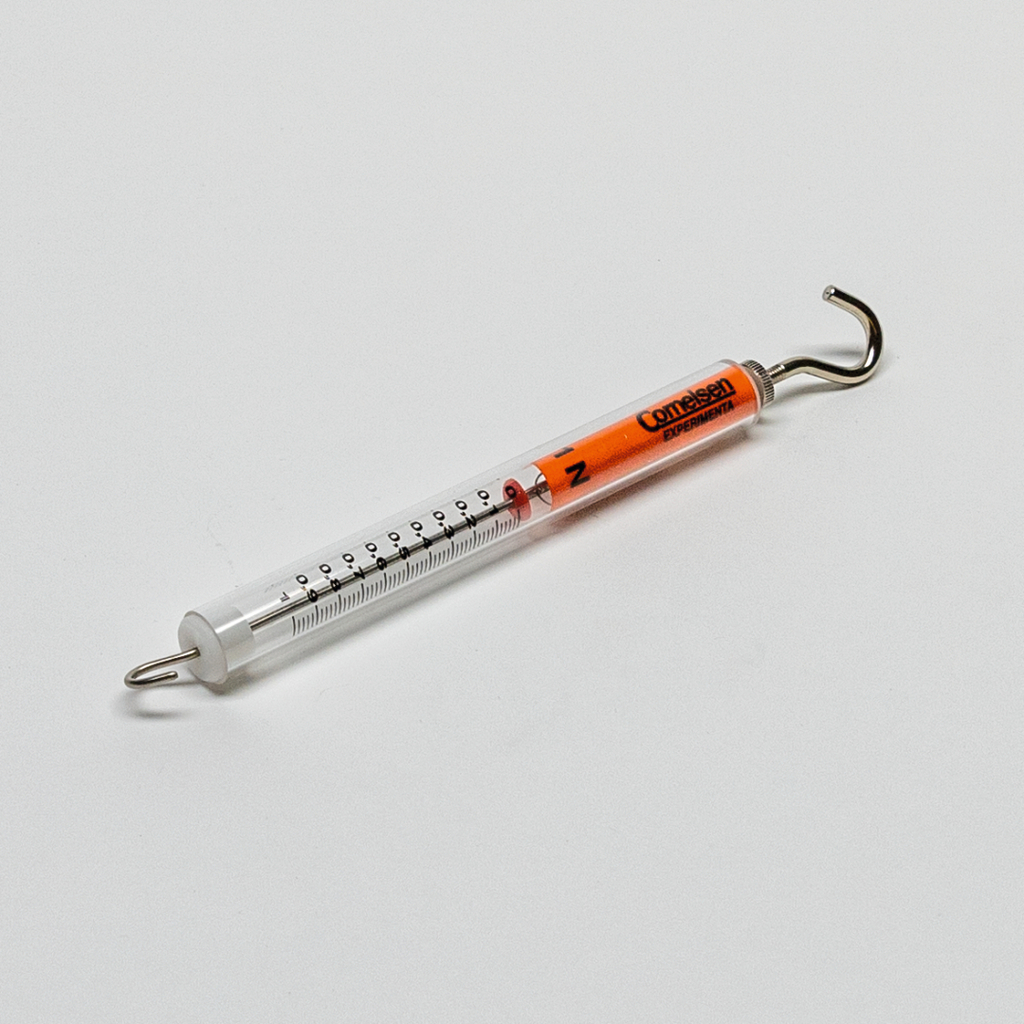 Das Bild zeigt ein Experimentiergerät, das vermutlich zur Messung von Kräften oder Gewichten verwendet wird. Es besteht aus einem transparenten Zylinder mit einer Skala und einem Haken an einem Ende, um Objekte zu wiegen oder zu testen.