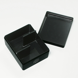 Das Bild zeigt eine schwarze Kunststoffbox mit einem herausnehmbaren Deckel und einer Trennwand im Inneren. Die Box dient wahrscheinlich zur Aufbewahrung von Experimentiermaterialien oder Zubehör für Bildungszwecke.