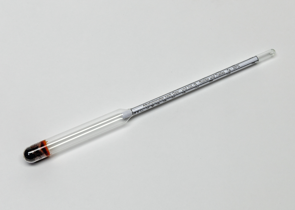 Das Bild zeigt ein Glasgerät, wahrscheinlich ein Thermometer oder einen Hydrometer, mit einer skalierten Messröhre und einer gefärbten Flüssigkeit am unteren Ende. Es dient zur Durchführung von Experimenten im Bildungswesen, insbesondere in den Naturwissenschaften.