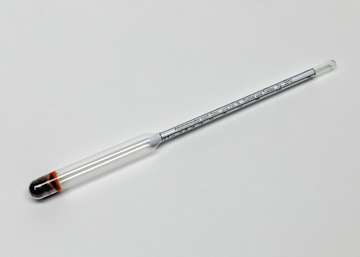 Das Bild zeigt ein Glasgerät, wahrscheinlich ein Thermometer oder einen Hydrometer, mit einer skalierten Messröhre und einer gefärbten Flüssigkeit am unteren Ende. Es dient zur Durchführung von Experimenten im Bildungswesen, insbesondere in den Naturwissenschaften.