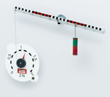 Das Bild zeigt eine experimentelle Einrichtung zur Demonstration von Kräften. An einer horizontalen Stange hängt eine Federwaage, die mit farbigen Gewichten verbunden ist, um Zugkraft zu messen.