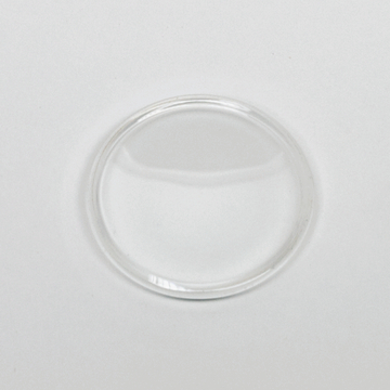 Das Bild zeigt eine klare, runde Glasplatte, die wahrscheinlich als Objektträger für mikroskopische Untersuchungen verwendet wird. Der Hintergrund ist hell und neutral, was den Fokus auf das Glasobjekt lenkt.