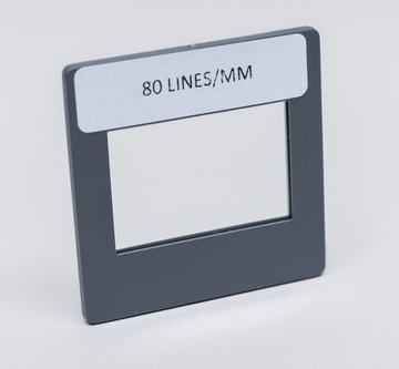 Das Bild zeigt einen rechteckigen Rahmen mit einer Öffnung in der Mitte. Auf dem Rahmen ist die Aufschrift „80 LINES/MM“ zu sehen, was auf seine Verwendung für optische Experimente hindeutet.