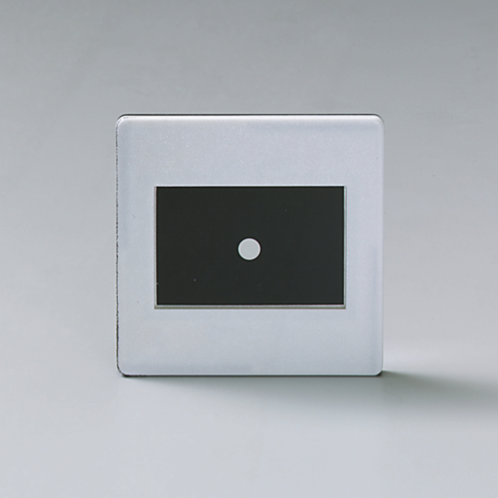 Das Bild zeigt ein rechteckiges Gerät mit einer glänzenden Oberfläche und einem zentralen schwarzen Bereich, in dem sich ein kleiner weißer Punkt befindet. Es scheint für experimentelle Zwecke in der Bildung konzipiert zu sein, möglicherweise für optische Versuche.