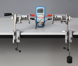 Das Bild zeigt zwei Motoren, die auf einem Tisch montiert sind, verbunden mit einem Messgerät. An einem der Motoren hängt ein Gewicht, das für Experimente zur Untersuchung von mechanischer Energie oder Drehmoment verwendet werden kann.