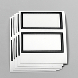 Das Bild zeigt mehrere identische, unbedruckte Papieretiketten mit schwarzen Rahmen. Diese Etiketten eignen sich für Beschriftungen und sind ideal für den Einsatz im schulischen Experimentierbedarf.