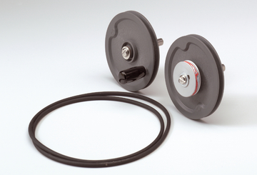 Das Bild zeigt zwei runde Experimentalgeräte mit einem Gummiring. Diese Komponenten scheinen Teil eines Versuchsaufbaus zu sein, der im Bildungswesen verwendet wird.