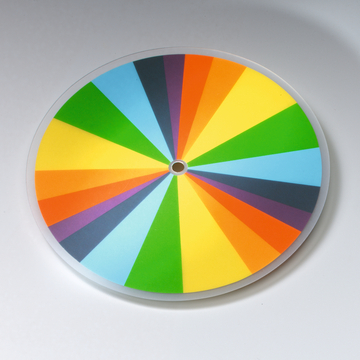 Das Bild zeigt einen farbenfrohen Kreisel mit einem kreisrunden Design, das in verschiedene segmentierte Farbbereiche unterteilt ist. Diese lebendigen Farben können für Experimente zur Farbtheorie oder zur Demonstration von Lichtstreuung genutzt werden.
