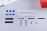 Das Bild zeigt verschiedene Experimentiermaterialien, darunter blaue Gummiteile, Metallstäbe, Schrauben, Unterlegscheiben und Lochschienen. Diese Komponenten sind vermutlich für technisches Lernen und Experimentieren im Bildungsbereich bestimmt.