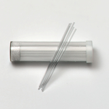 Das Bild zeigt ein durchsichtigen Behälter mit einem Plastikdeckel, der mehrere lange, dünne Glasstäbe enthält. Diese Stäbe sind vermutlich für Experimentier- oder Lehrzwecke in der Wissenschaftsbildung gedacht.