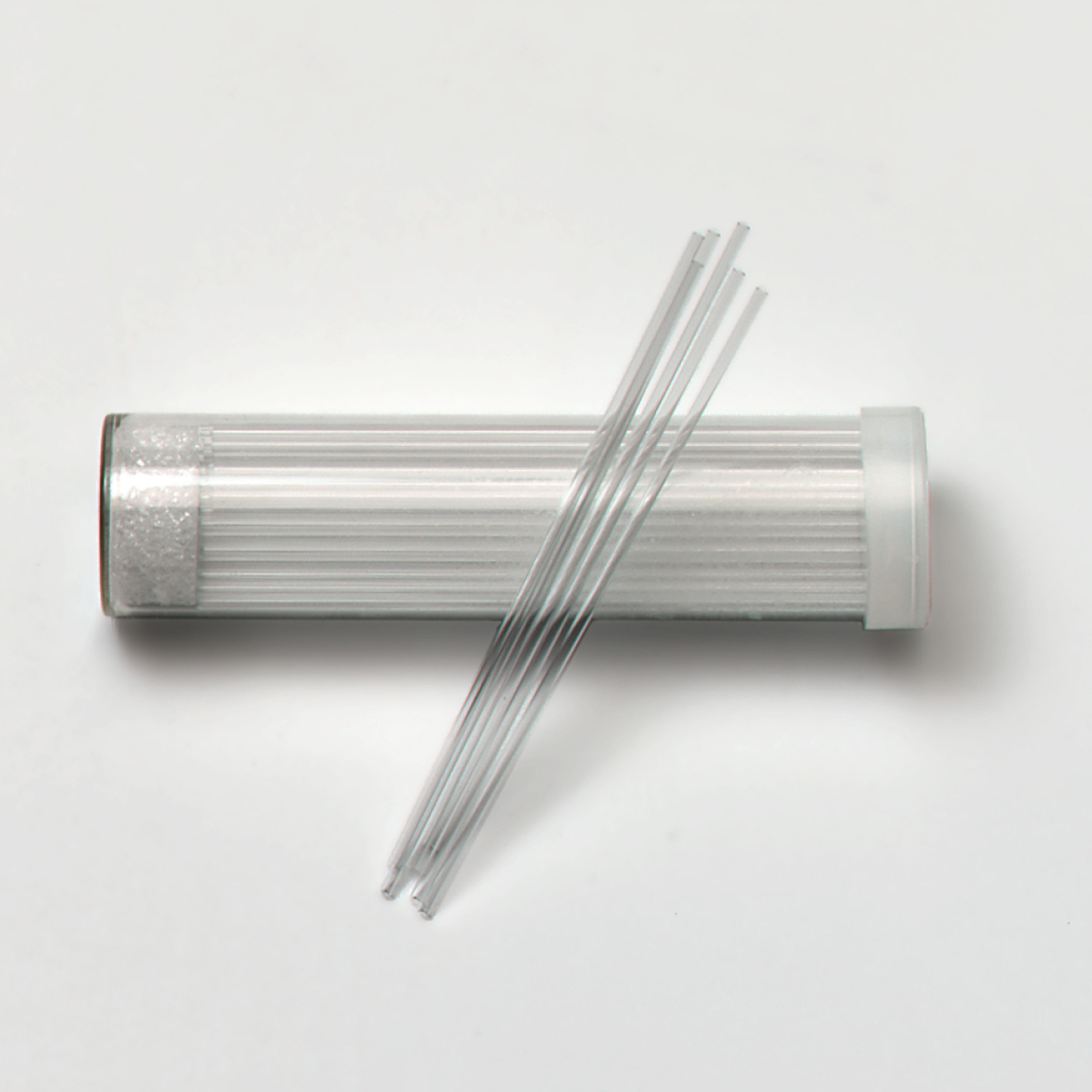 Das Bild zeigt ein durchsichtigen Behälter mit einem Plastikdeckel, der mehrere lange, dünne Glasstäbe enthält. Diese Stäbe sind vermutlich für Experimentier- oder Lehrzwecke in der Wissenschaftsbildung gedacht.