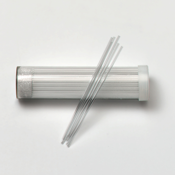 Das Bild zeigt ein durchsichtigen Behälter mit einem Plastikdeckel, der mehrere lange, dünne Glasstäbe enthält. Diese Stäbe sind vermutlich für Experimentier- oder Lehrzwecke in der Wissenschaftsbildung gedacht.