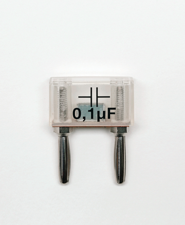 Das Bild zeigt einen Elektrolytkondensator mit einer Kapazität von 0,1 µF, der durch seine transparente Hülle sichtbar ist. Die Anschlüsse sind aus Metall und deutlich ausgeprägt, was ihn für Experimente im Bildungswesen geeignet macht.