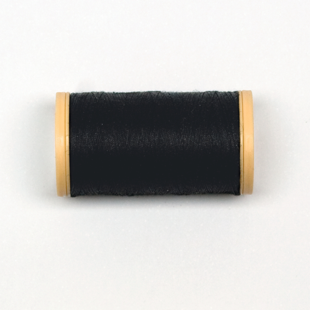 Das Bild zeigt eine Spule mit schwarzem Faden, die auf einer weißen Oberfläche liegt. Die Spule hat an beiden Enden gelbe Plastikkappen, die den Faden halten und schützen.