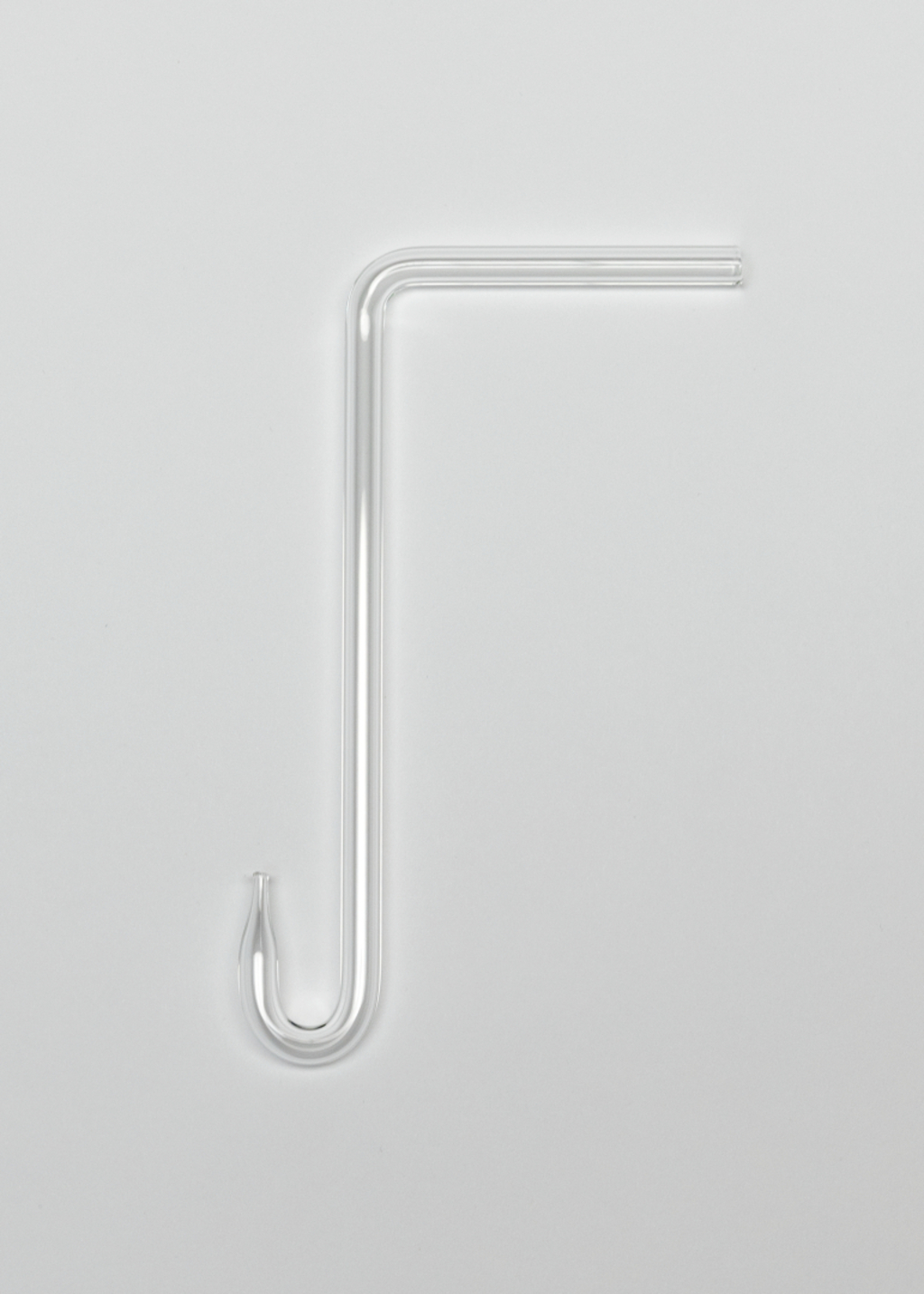 Das Bild zeigt ein klares, gebogenes Glasrohr mit einem hakenartigen Ende. Es ist wahrscheinlich ein Laborglasgerät, das in Experimenten verwendet wird, um Flüssigkeiten zu transportieren oder zu sammeln.