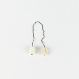 Das Bild zeigt zwei kleine, zylindrische Objekte, die durch einen Draht miteinander verbunden sind. Sie scheinen aus unterschiedlichen Materialien gefertigt zu sein und könnten für experimentelle Zwecke im Bildungsbereich verwendet werden.