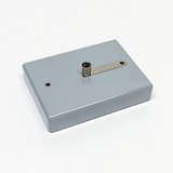 Das Bild zeigt ein graues, rechteckiges Gerät mit einer Metallplatte und einem Ifassansatz. Es dient wahrscheinlich als Experimentiermaterial für den Bildungsbereich, möglicherweise zur Durchführung von physikalischen Tests oder Experimenten.