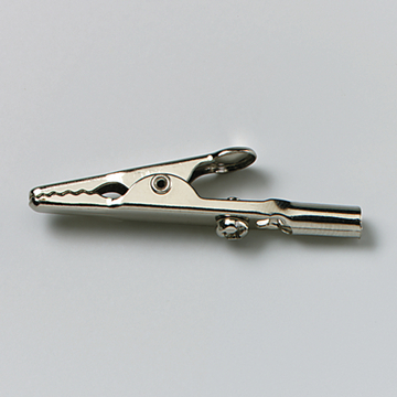 Das Bild zeigt eine metallische Krokodilklemme, die typischerweise in Experimenten verwendet wird. Sie dient zur elektrischen Verbindung von Bauteilen oder zur Befestigung von Drähten in der Wissenschaftsausbildung.