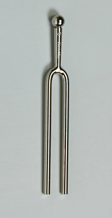 Das Bild zeigt ein Stahlgabel-Tonmittel, das aus einem langen, geschwungenen Metallrohr besteht, das oben mit einer kleinen Kugel endet. Es wird häufig in der Musikausbildung verwendet, um die Tonhöhe zu bestimmen und als Stimmgerät zu dienen.