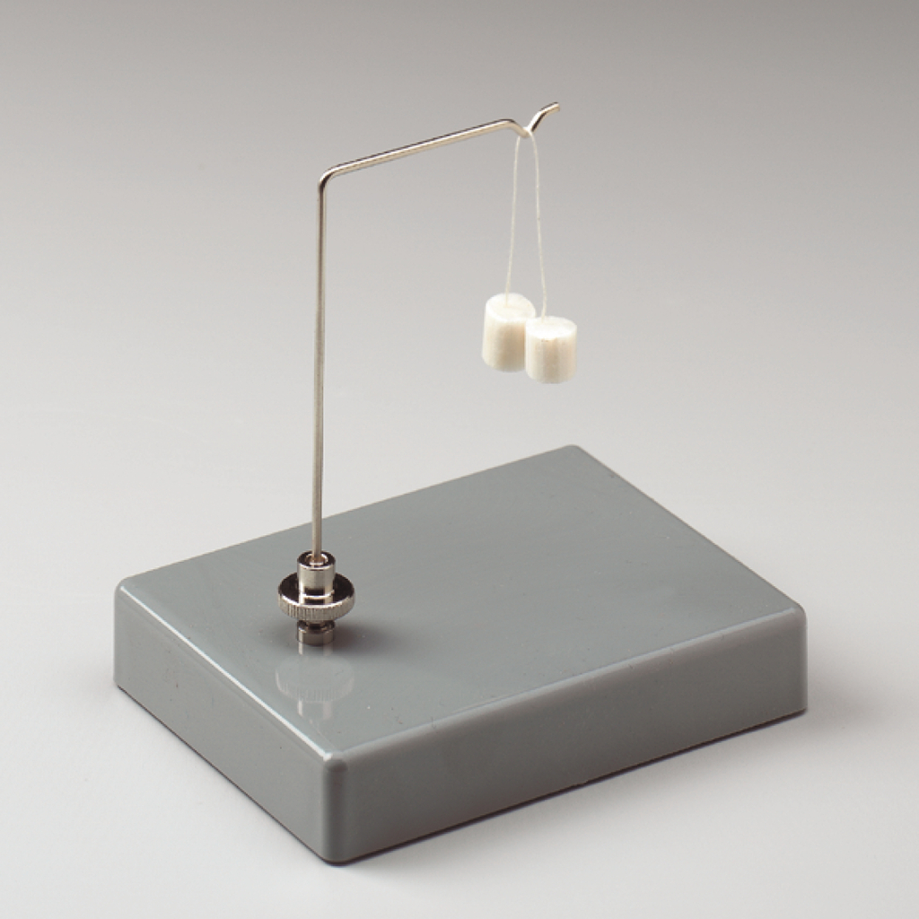 Das Bild zeigt eine einfache Hebelvorrichtung mit einem Metallbügel, der zwei kleine, weiße Gewichte trägt. Die Konstruktion steht auf einer grauen Basis und wird häufig für experimentspezifische Anwendungen im Bildungsbereich verwendet.