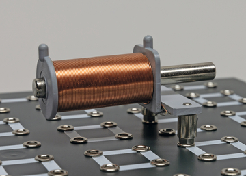 Das Bild zeigt eineKupferspule, die auf einer experimentellen Plattform montiert ist. Die Struktur enthält Verbindungsstellen, die zur Durchführung von Experimenten in der Elektro- und Magnetfeldforschung genutzt werden können.