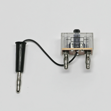 Das Bild zeigt ein Experimentiergerät mit einem transparenten Gehäuse, zwei Anschlüssen und einem Drehschalter. Es wird vermutlich für verschiedene physikalische Experimente im Bildungsbereich eingesetzt.