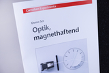 Das Bild zeigt einen Katalogeintrag für ein Demo-Set zur Optik mit dem Titel „Optik, magnethaftend“. Es enthält eine Abbildung eines optischen Experiments, das möglicherweise als Lernhilfe für das deutsche Bildungswesen dient.